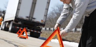 Camionneur en panne : s’arrêter ou continuer sa route? Camionneur en panne sur la route qui pose ses triangles de sécurité.