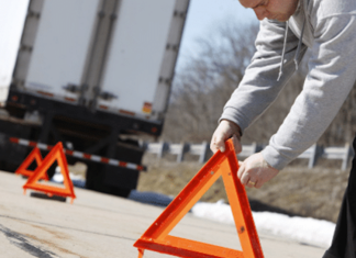 Camionneur en panne : s’arrêter ou continuer sa route? Camionneur en panne sur la route qui pose ses triangles de sécurité.