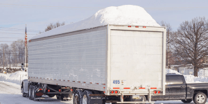 Camion semi-remorque avec beaucoup de neige sur son toit, représentant les dangers de ne pas déneiger ou déglacer en hiver.