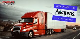 Transport routier : l’Arkansas veut reprendre le contrôle des camionneurs étrangers et frapper fort Camion roulant sur une autoroute avec un panneau « Welcome to Arkansas », illustrant le débat sur les camionneurs étrangers et les nouvelles lois proposées en transport routier.