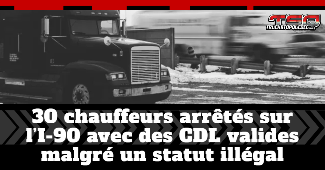 camion lourd roulant sur une route enneigée, avec un deuxième camion flou en arrière-plan pour illustrer le mouvement. En bas de l’image, on voit un bandeau noir avec le texte : « 30 chauffeurs arrêtés sur l’I-90 avec des CDL valides malgré un statut illégal », accompagné du logo Truck Stop Québec.