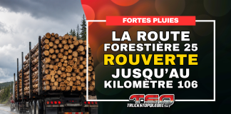 La route forestière 25 rouverte jusqu’au kilomètre 106 Camion forestier chargé de billots circulant sous la pluie, avec l’annonce de la réouverture de la route forestière 25 jusqu’au kilomètre 106.